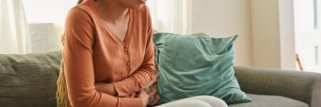 Woman experiencing IBS while lying on the sofa at home