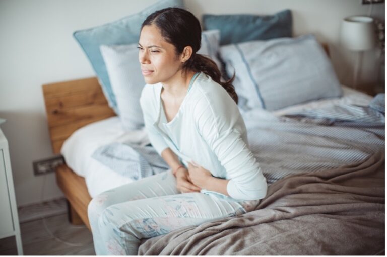 Distressed woman at home holding her stomach and suffering from internal bleeding stomach symptoms